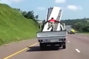 くっそ危ねえ。トラックの荷台で荷物を押さえていた男が飛ばされそうになる瞬間。