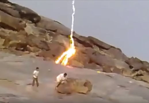 岩場で遊ぶ人たちのすぐ近くに落雷した稲妻が岩の表面を伝わる凄い映像。