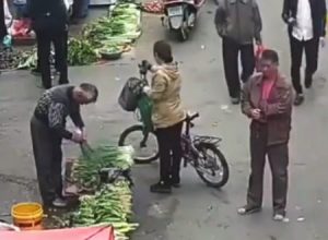 箸を使って女性のポケットから携帯電話を盗み取る中国の「箸スリ」の犯行の瞬間。