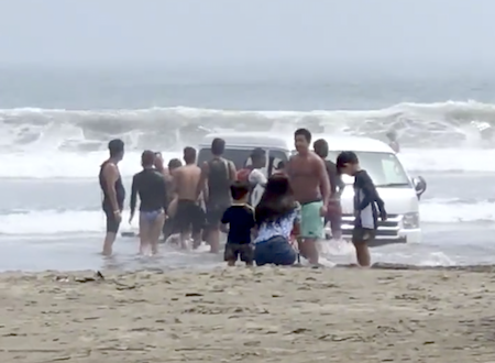 お盆休みの大洗海岸でハイエースを埋める遊びをしている若者たちが撮影される。