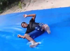 泥酔してグロッキー状態な男を巨大ウォータースライダーに突き落とす極悪な男たち。