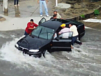 洪水で取り残された車の中から女性を救出しようとするドラマチックな映像。